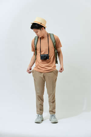 Young Asian tourist man lost his money and feel disappointed while standing over white background.