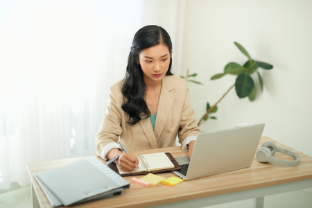 Asian businesswoman mother working at home with notebook computer. Concept for home based work.の写真素材