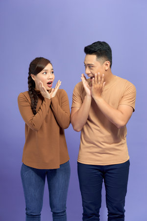 Amazed asian couple expressing shock, purple studio backgroundの写真素材