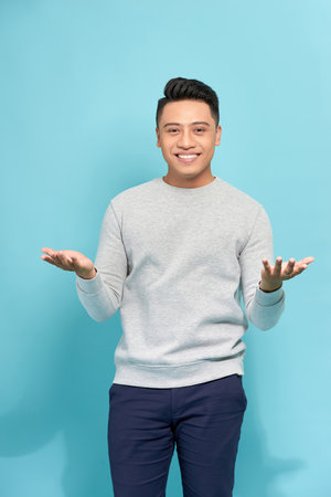 A standing young man raising hands as he saying surprise, isolated on a Blue background.の写真素材