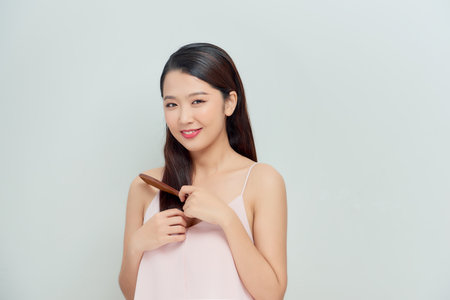 Portrait of cute young woman on white background combing hair.の写真素材