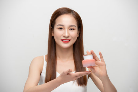 Young Asian woman holding cosmetics product, bottle over white background.の写真素材