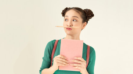 Photo of funny foolish student lady hold journal book not reading playing pen make fake mustache isolated over white backgroundの写真素材