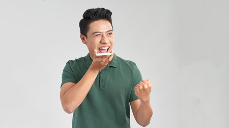 Photo of handsome excited man expressing surprise on face and gesturing while speaking on telephone...