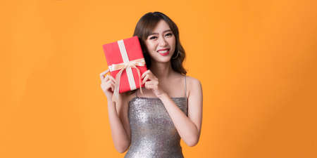 Beautiful happy woman wearing sparkle dress with gift box at celebration partの写真素材