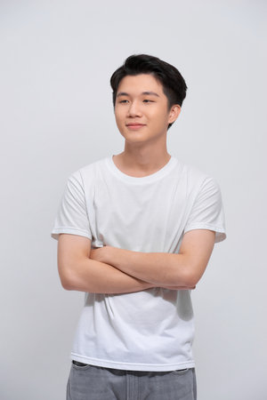 Portrait of young asian man isolated on white background, standing with crossed arms, smiling and...