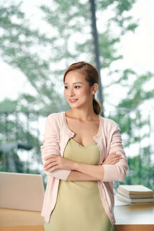 cheerful businesswoman standing with crossed arms in officeの写真素材
