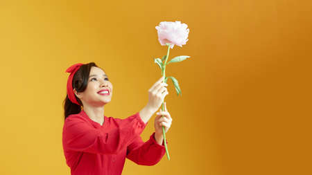 Pretty girl holding a peony on yellow backgroundの写真素材