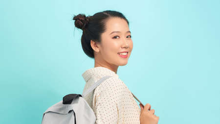 Young woman over isolated blue background with backpackの写真素材