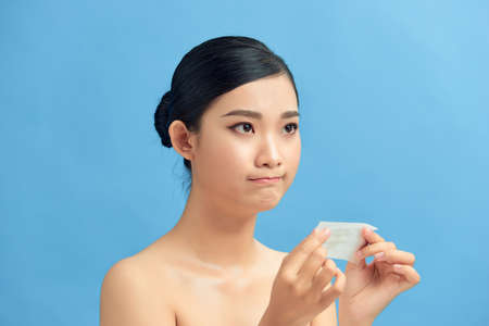 Young asian skin care woman upset after use oil blotting paper on her faceの写真素材
