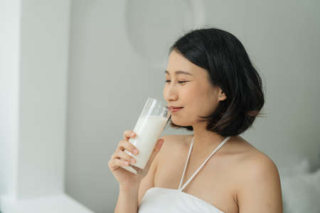 Young pregnant woman with glass of milk standing
