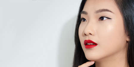 Smiling lovely young woman touching face with clasped handsの写真素材