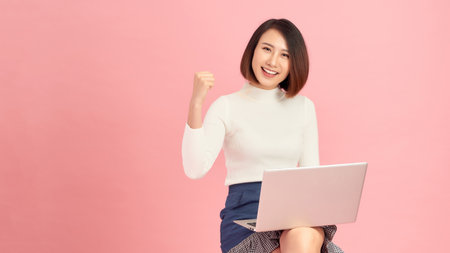 Smiling lady with a laptop won, emotionally rejoicing.の写真素材