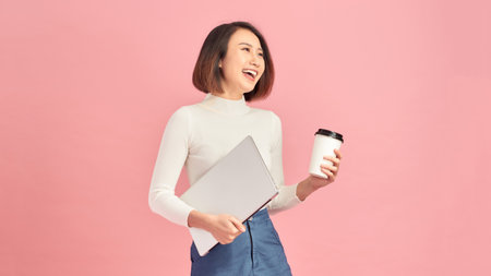 Young beautiful woman drinking coffee holding clipboard isolated over pink backgroundの写真素材