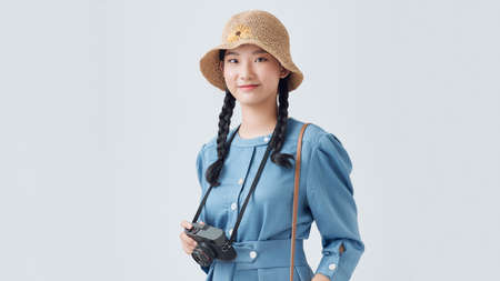 Attractive energetic Asian woman happily holding cemara isolated on gray backgroundの写真素材