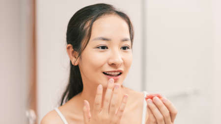 a young woman is painting lip balm in bathroom at homeの写真素材