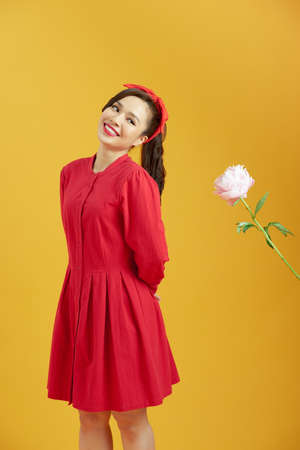 Man giving pink peony flowers and shy woman isolated on yellow backgroundの写真素材