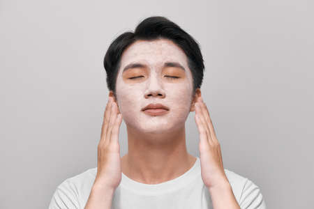 Handsome man with clay mask on his face against white backgroundの写真素材