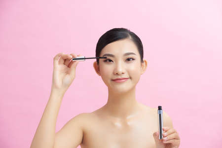 Young woman during make-up session isolated on pink