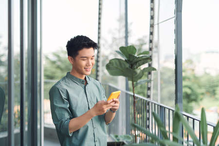 Asian young man using smartphone on balcony
