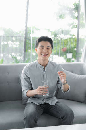A handsome man holding up vitamin pillの写真素材