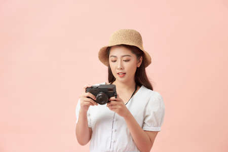 Woman traveler with a camera, pink background