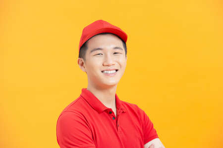 Portrait of attractive content virile cheerful guy mailman folded arms isolated over vibrant yellow color backgroundの写真素材
