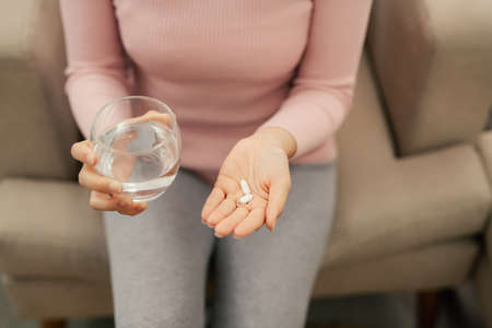 Close up photo of one round white pill in young female hand