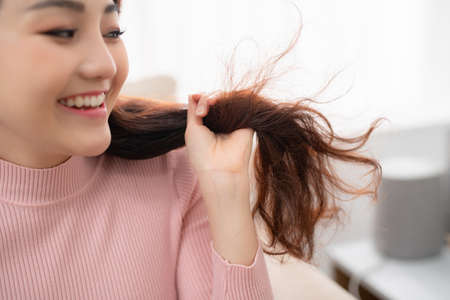 portrait of beautiful happy woman drying her long hair with dryerの写真素材