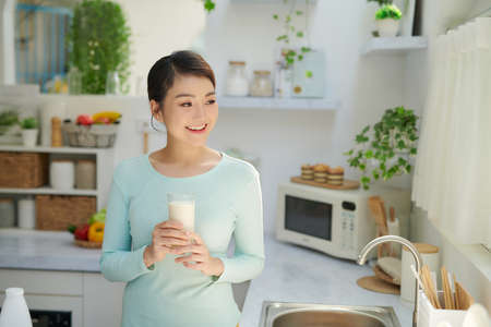 Smiling attractive woman having breakfast in kitchen interiorの写真素材