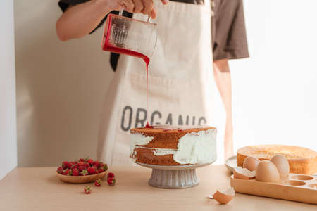 fresh sponge cake with raspberry syrup being poured over the top. Making red velvet or sponge cake processの写真素材