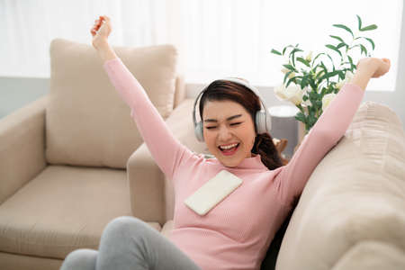 Image of delighted young woman singing while using headphones and cellphoneの写真素材