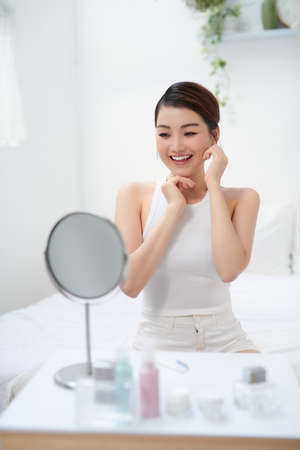 Image of pleased asian woman smiling and looking at mirrorの写真素材