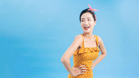 Young woman in black dots dress on blue background