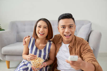 Couple using a remote control while sitting on floorの写真素材