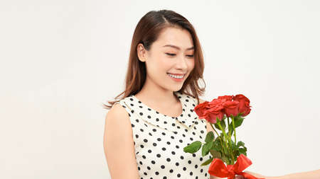 Charming tender girl holds red roses in her hands and looks thoughtfully to the side. Photo on a white background.の写真素材