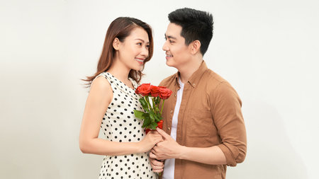 Young beautiful asian couple with flowers isolated on whiteの写真素材