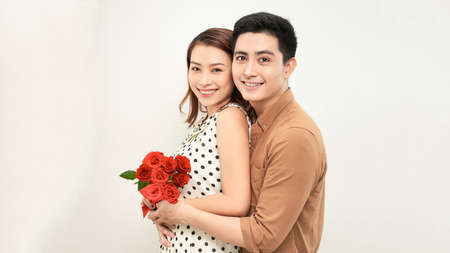 Young beautiful asian couple with flowers isolated on whiteの写真素材
