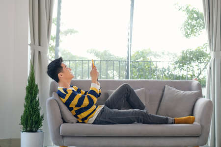 Young male sitting on the floor in the living room and having video call via phone