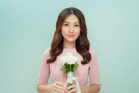 beautiful young woman with a bouquet of roses flowers on a light backgroundの写真素材