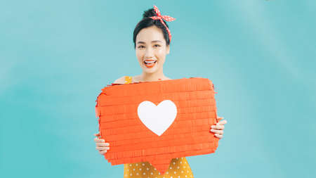 Attractive woman holding heart symbol of like and love social media notification icon happy with followers and fans on the internet.の写真素材