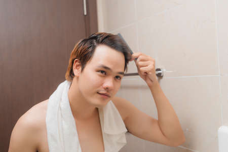 Reflection of Young Man Bushing Hair in Mirror