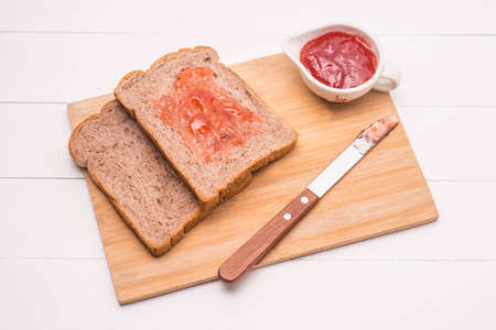 Toast with strawberry jam on a plate on table.