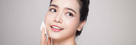 Happy smiling beautiful asian woman using cotton pad cleaning skin.の写真素材