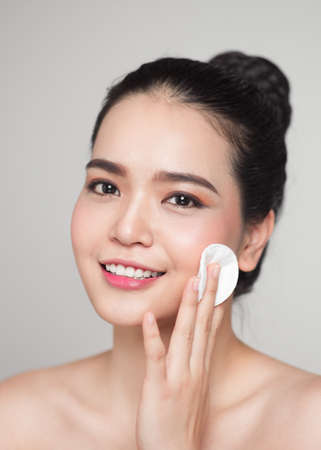 Happy smiling beautiful asian woman using cotton pad cleaning skin.の写真素材