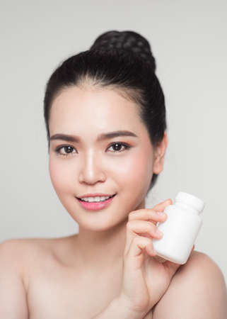 Healthy happy asian woman with pills bottle in hand.の写真素材