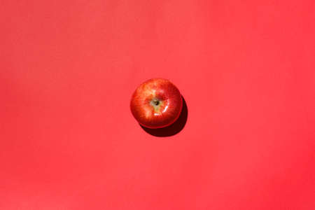 Red apple isolated in studio with red backgroundの写真素材