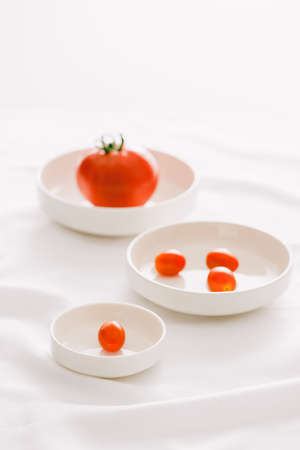 Fresh red tomatoes in white plate on white tableの写真素材