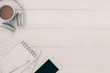 Headphone and mobile phone on white table with notepad.