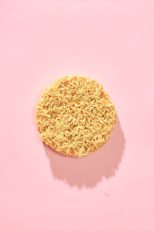 Instant pasta in the form of a circle on a pink backgroundの写真素材